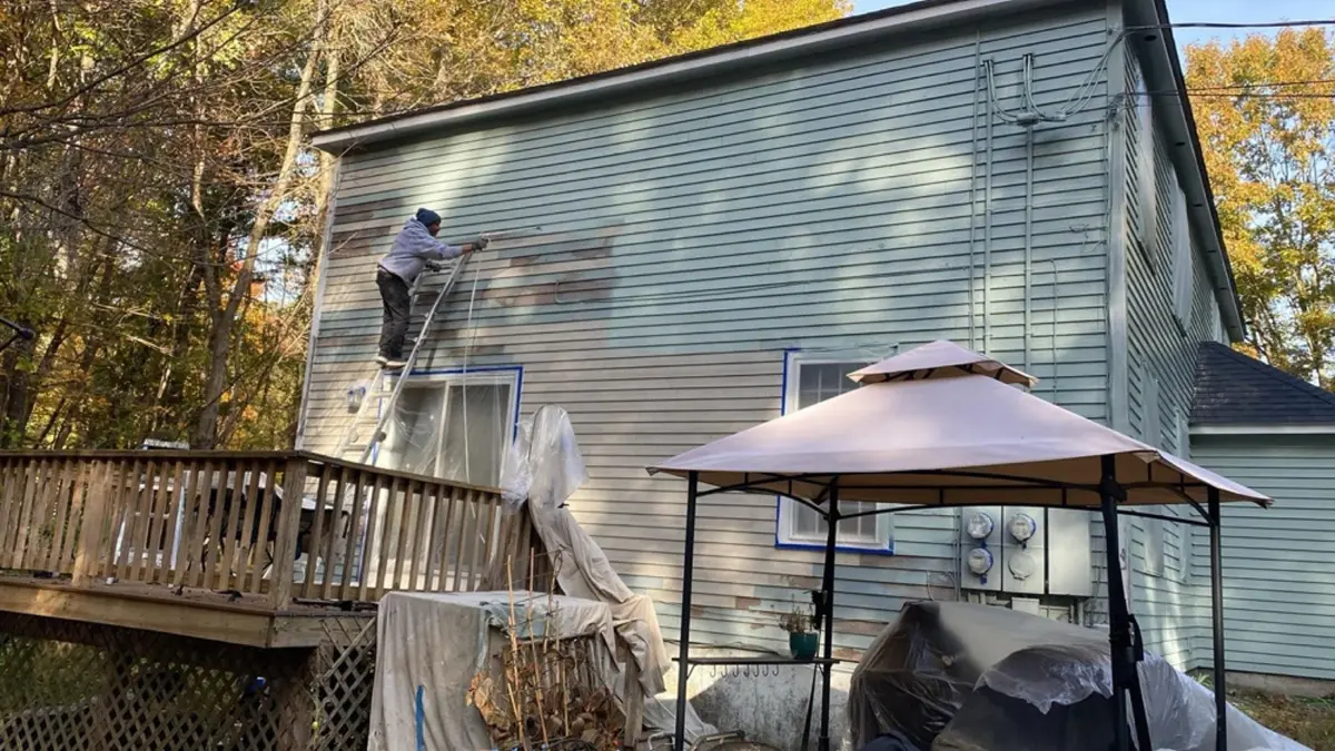 A painter prepping and painting the exterior of a Massachusetts home